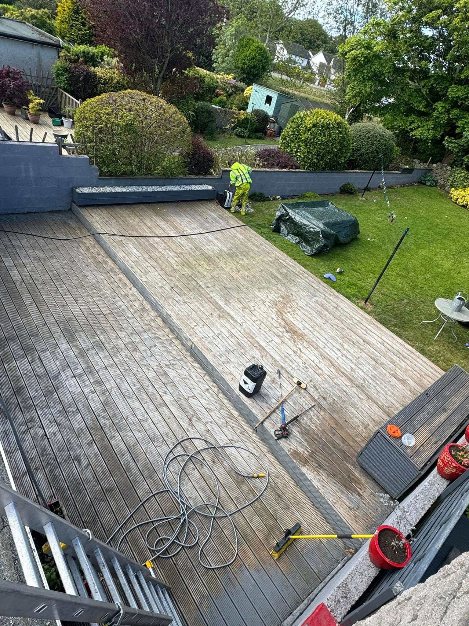 Timber decking part-way through cleaning, clean stripes showing