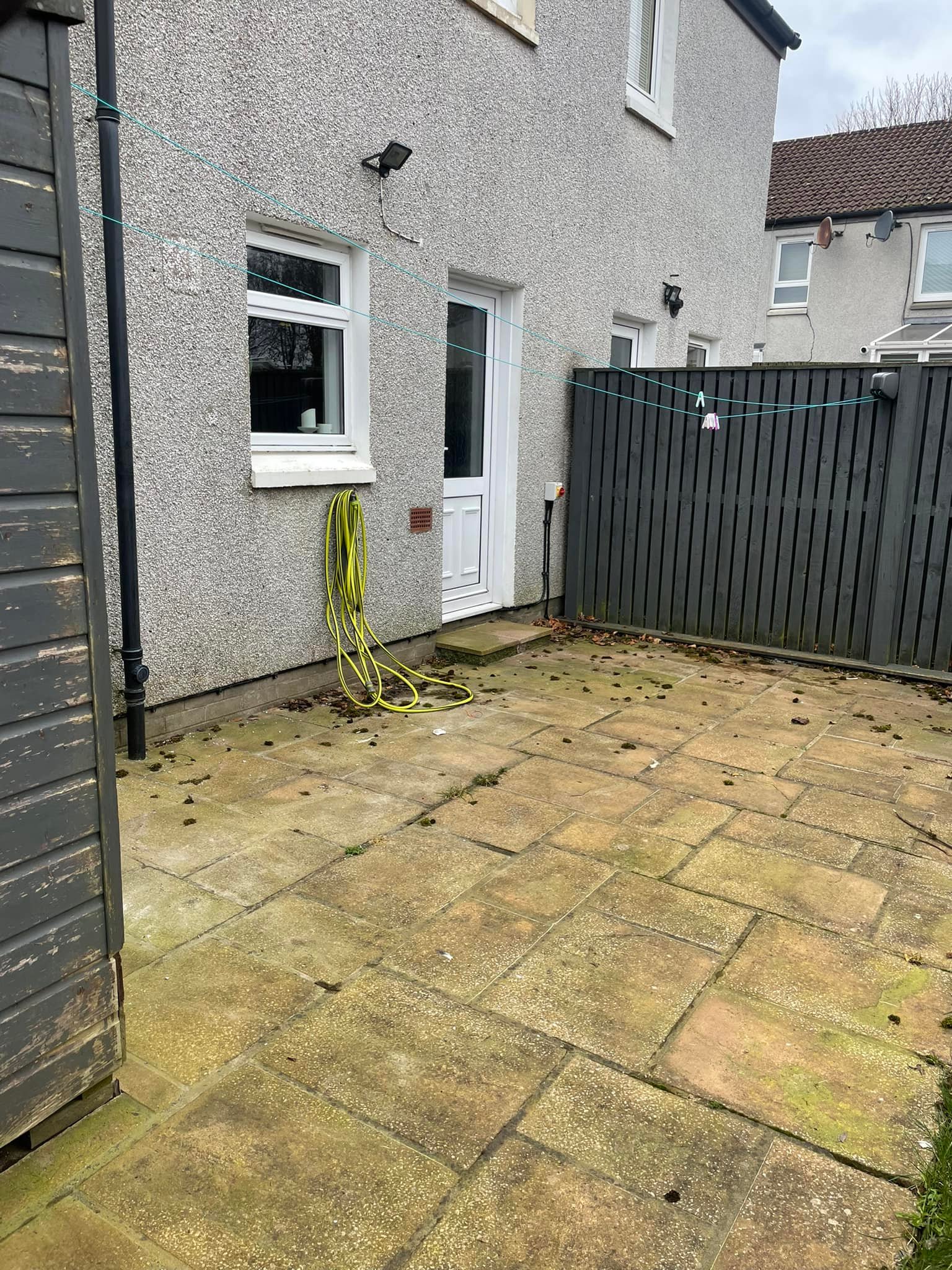 Same rear patio before cleaning, slabs green and moss-spotted
